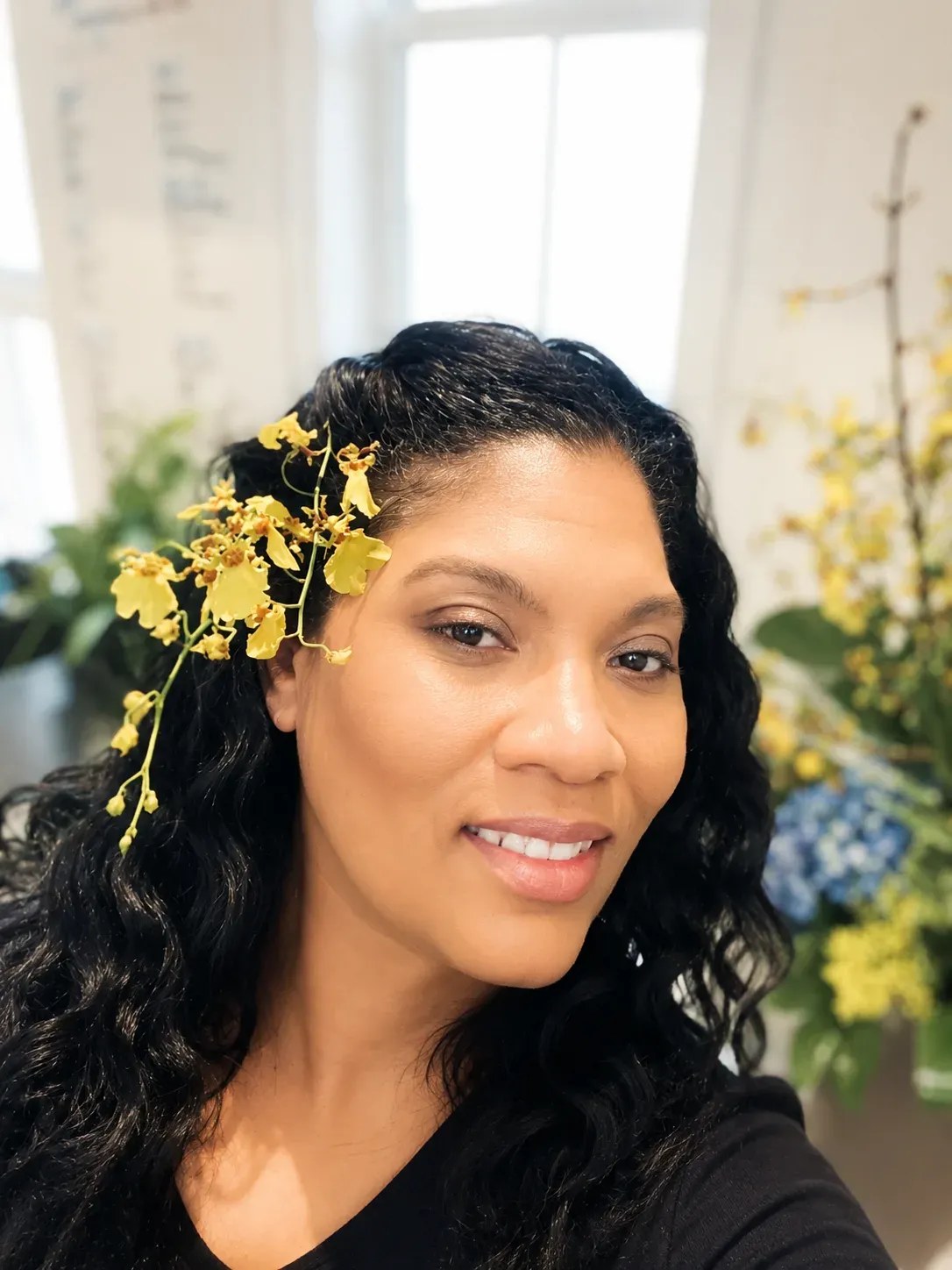 Veronica Sallee, florist and owner of The Blooming Bohemian, smiling with flowers in her hair
